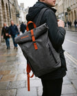Custom roll-top daypack with printed logo, worn on city street